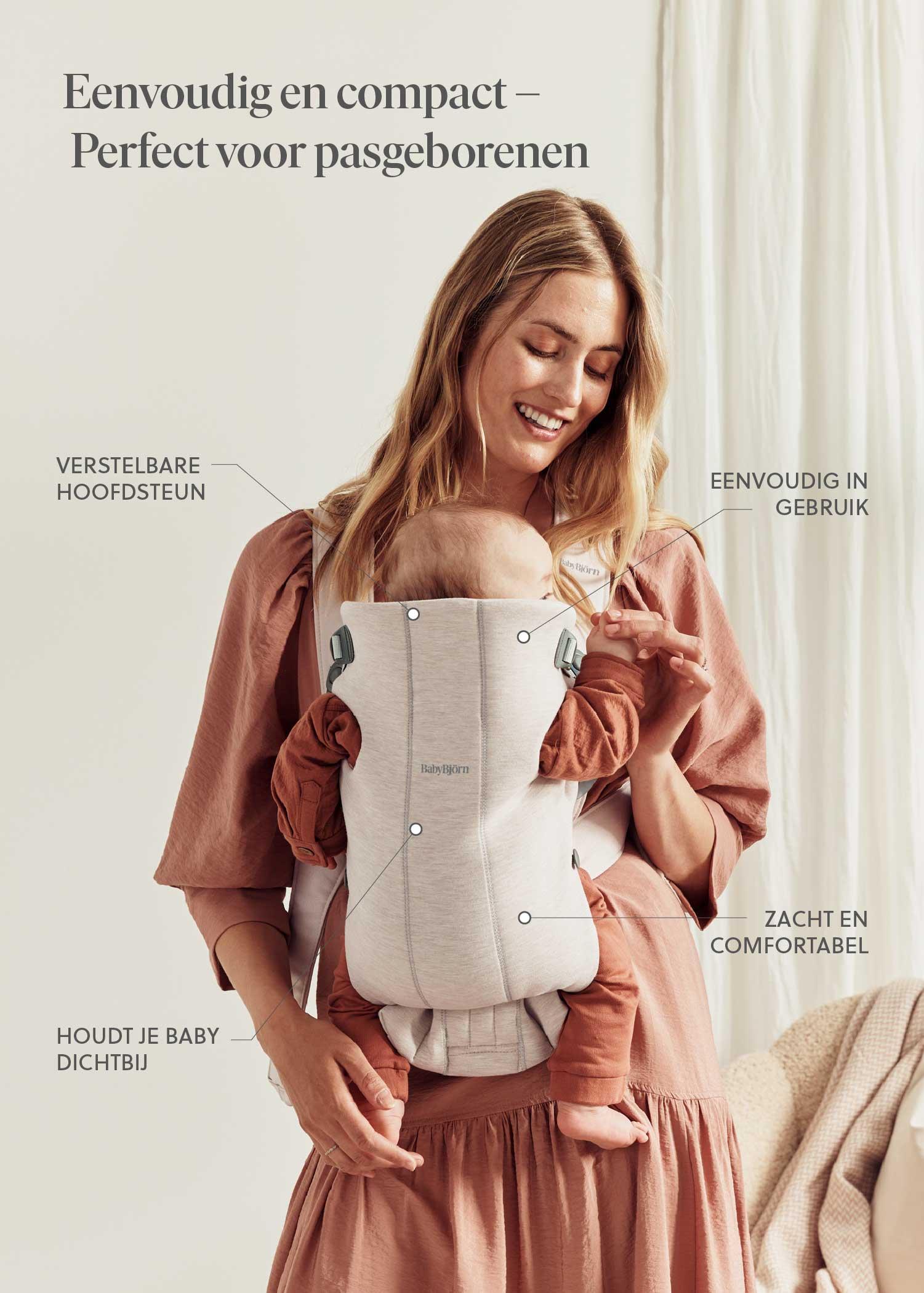 Woman in pink dress holding a baby in a gray baby carrier. Text highlights features of the carrier in Dutch, such as adjustable headrest and comfort.